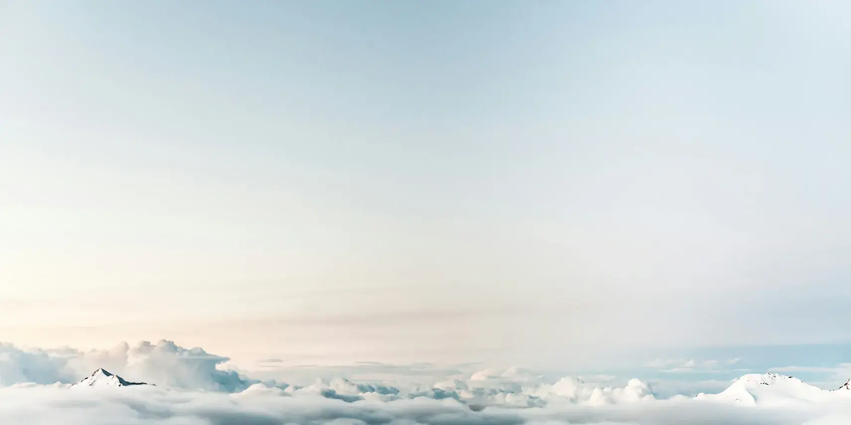 A clear blue sky with white mountains along the ground