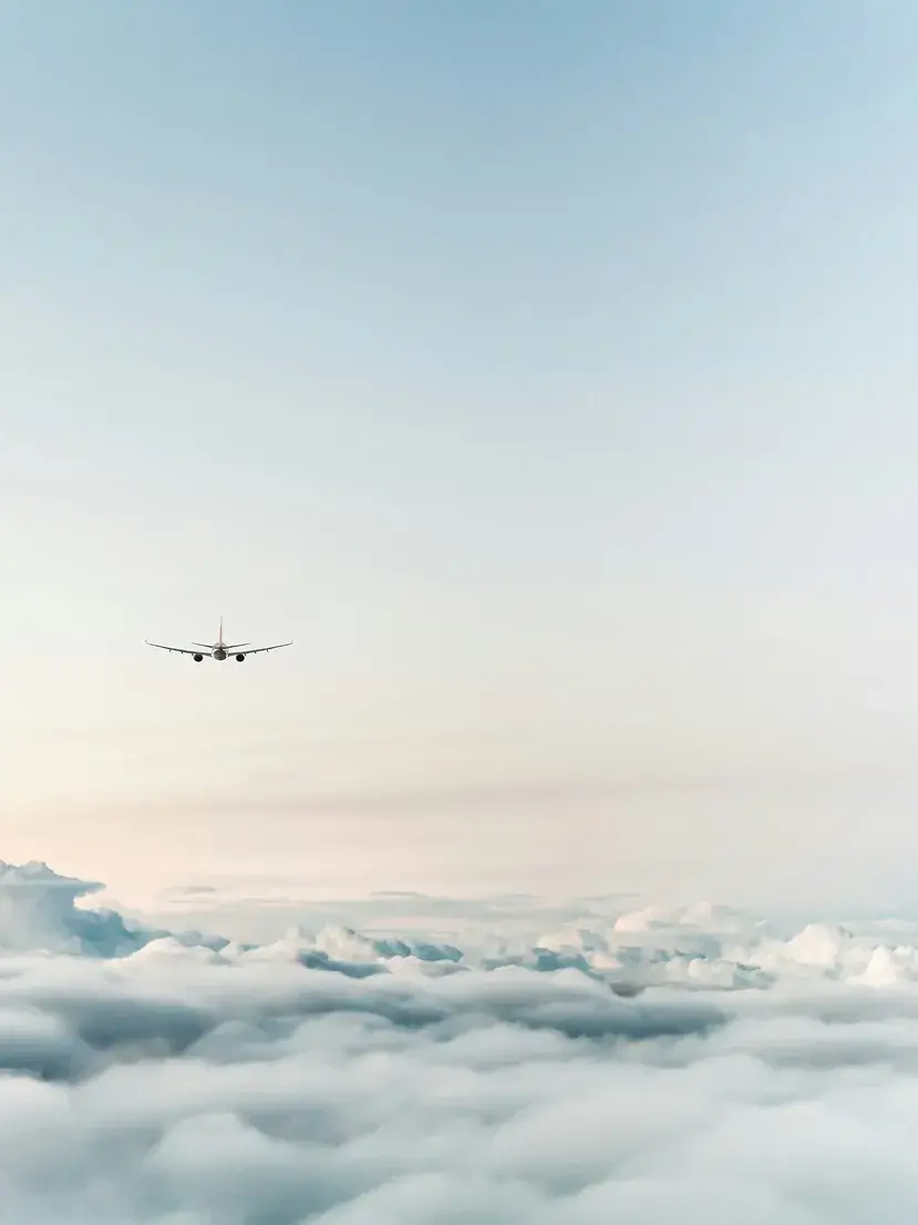 An airplane flying in the distance above a cloudy sky