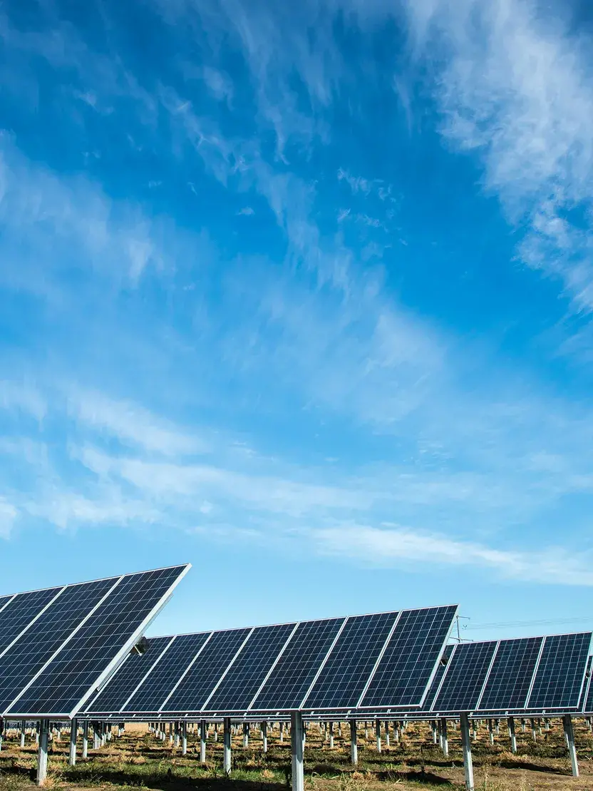 Field of solar panels below a blue sky